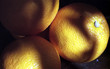 three oranges sitting on an old table in the shade