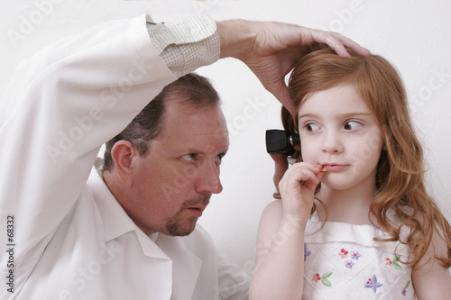 Foto: doctor looking in little girl's ear doctor looking in little girl's ear