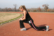 athletic young woman stretching at the track