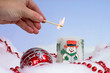 person lighting christmas candle with decorations around it