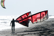kitesurfer walking along the sandy beach at the end of a busy da