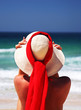 girl sitting on sandy beach in the sun adjusting hat. blue sky, girl sitting on sandy beach in the sun adjusting hat. blue sky,