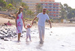 young, healthy family walking along a sunny beach