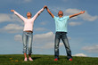 couple standing on grass with raised arms