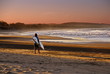 Photo: surfer goes to the beach at sunset surfer goes to the beach at sunset
