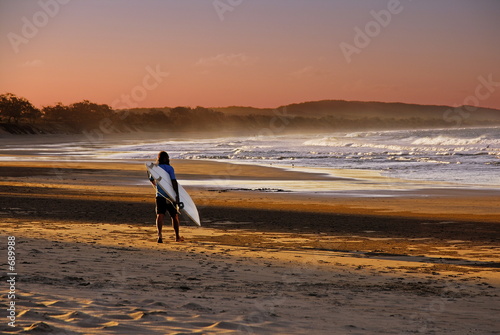 surfer goes to the beach at sunset
