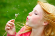 young teenager blowing a dandelion