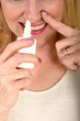 woman spraying nasal spray in nose 2 woman spraying nasal spray in nose 2