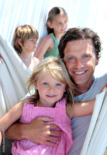 Photo: young father and children sitting in a hammock on vacation young father and children sitting in a hammock on vacation