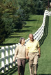 couple walking a white fence in the country