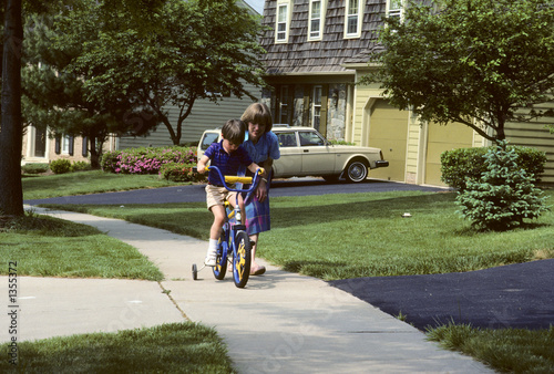 Photo: mother helps son learn to ride a bike mother helps son learn to ride a bike