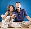 young shocked couple on carpet with remote control