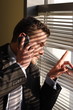 Foto: business man on phone looking through window blin business man on phone looking through window blin