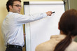 Photo: man explaining an idea on flip chart to woman man explaining an idea on flip chart to woman