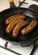 sausages in a black frying pan on gas stove sausages in a black frying pan on gas stove