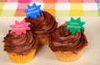 closeup of three chocolate frosted cupcakes with "happy birthday