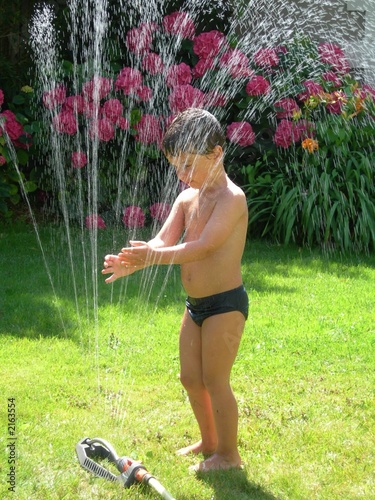 Photo: jeune garçon jouant avec un arrosage auromatique jeune garçon jouant avec un arrosage auromatique