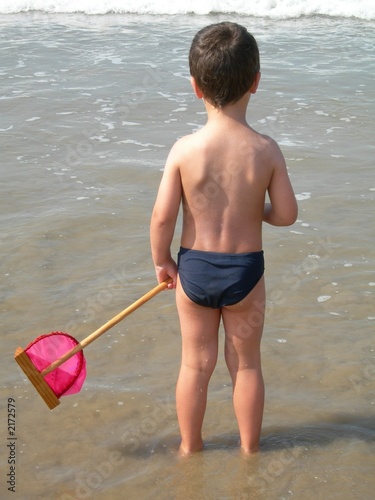 Photo: jeune garçon avec une épuisette au bord de l'eau jeune garçon avec une épuisette au bord de l'eau