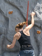 a teenage girl climbing up an artificial rock wall