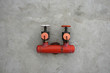 red iron valve on a cement wall