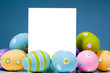 brightly colored easter eggs surrounding white, blank notecard