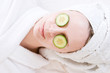 woman with a facial mask and cucumber on her face