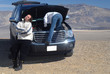 woman trying to fix car while husband relaxes