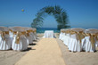 beach wedding with chairs, palm arch and ocean in