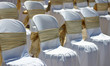 white chairs with gold ribbon at a beach wedding