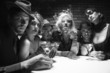 retro males and females sitting at table in lounge.