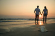 Couple holding hands on beach.