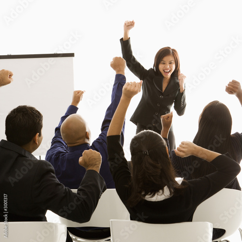 Photo: businesswoman leading presentation while audience cheers. businesswoman leading presentation while audience cheers.