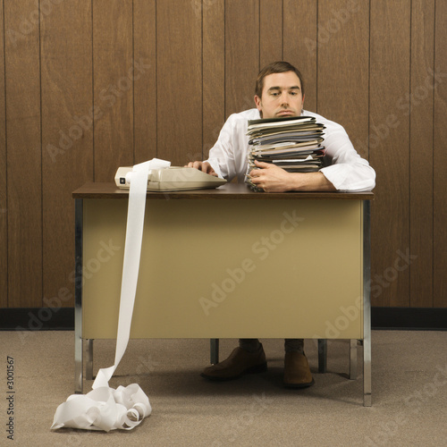 man holding stack of paperwork with hand on calculator with long