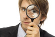 businessman looks through magnifying glass