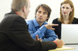three workers talk near a desk three workers talk near a desk