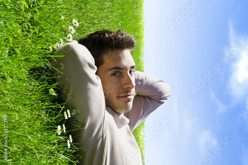 jeune homme sourire détendu herbe et ciel bleu