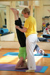 the woman-teacher helps the woman-yoga to stand on