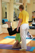 the woman-teacher helps the yoga to stand on a hea