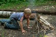 boy kindles bonfire in the deciduous forest