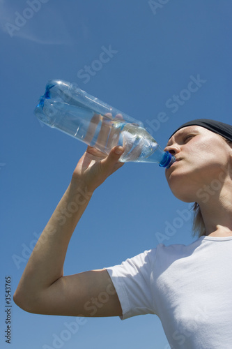 sporty woman have water from bottle over blue sky