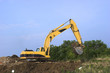 Large yellow  excavator scooping dirt at a construction site