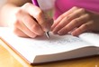 Young female is writing notes and planning her schedule.