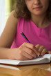 Young female is writing notes and planning her schedule.