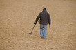 Man with metal detector on anonymous beach. Copyspace