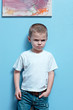 Little boy mad look on face standing against a wall
