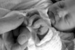 newborn girl holding on to her daddy's finger while sleeping