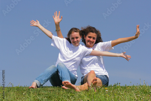 Photo: Two teen girls wave hands against a blue sky Two teen girls wave hands against a blue sky