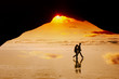 View from cave to young couple walking a beach at sunset