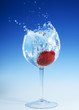 Large strawberry splashing into glass of refreshing clear liquid