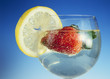 Strawberry in bubbly water with a slice of lemon on the glass